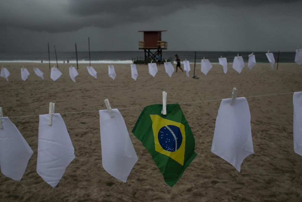 Một lá cờ Brazil được treo tại bãi biển Copacabana giữa những chiếc khăn trắng tượng trưng cho những người đã chết vì COVID-19 ở Rio de Janeiro, Brazil