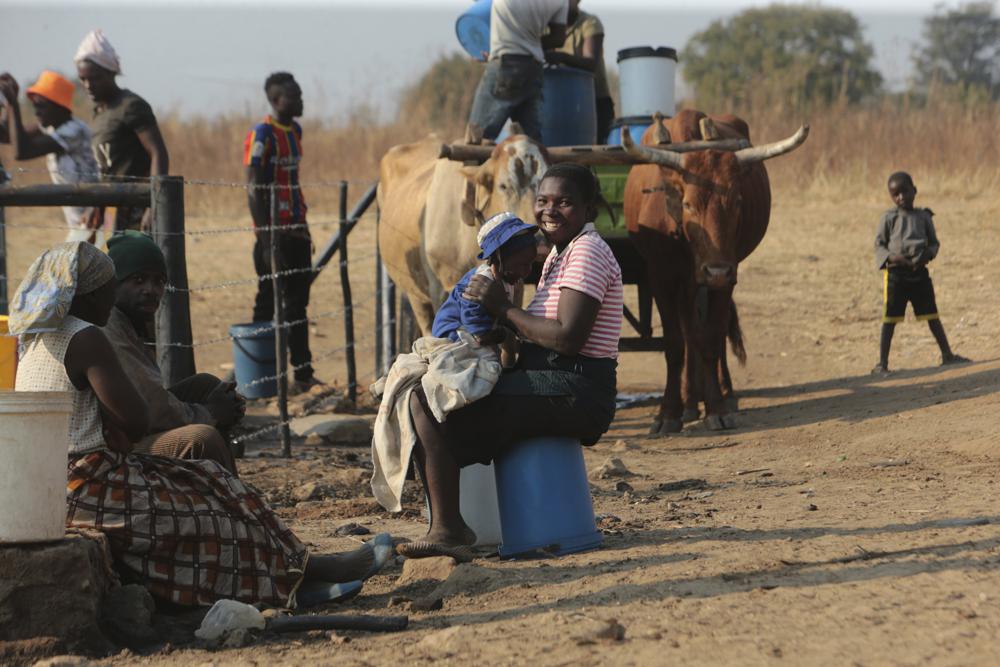 Một người phụ nữ mỉm cười khi chơi với con tại một điểm lấy nước ở ngoại ô thủ đô Harare