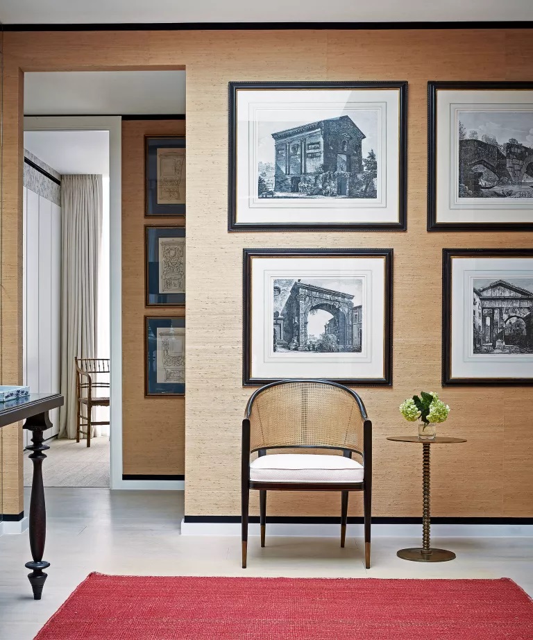 10. LIÊN KẾT LỐI VÀO CỦA BẠN VỚI PHẦN CÒN LẠI CỦA NGÔI NHÀ Cho dù bạn bị thu hút bởi những bức tường theo phong cách phòng trưng bày hay những cách treo đồ truyền thống hơn, nghệ thuật sẽ làm sống động một lối vào nhỏ và tạo nên tông màu cho ngôi nhà. Trong nội thất này của Paolo Moschino cho Nicholas Haslam, các bản in lịch sử được treo một cách có trật tự là đặc biệt thanh lịch và kết nối hai khu vực khác nhau của một lối vào duy nhất.  Giấy dán tường màu caramel - đây là hình nền Haruki trong Oatmeal của Schumacher - đảm bảo căn phòng không có vẻ quá lạnh lẽo hoặc công ty. Giúp liên kết hai phong cách là các khung tối thông minh, tương phản với phần trang trí trên giấy dán tường (ruy băng grosgrain của Pháp bởi Samuel & Sons) và đồ nội thất bằng gỗ tối màu.