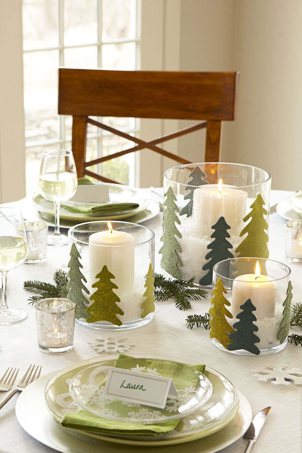 Tạo vẻ ngoài vui tươi, xảo quyệt bằng cách trang trí bàn của bạn với những cơn bão thủy tinh được trang trí bằng những cây thông Noel bằng vải nỉ. Chơi chủ đề màu xanh lá cây với bộ bát đĩa bổ sung, khăn ăn bằng vải và cành vân sam.