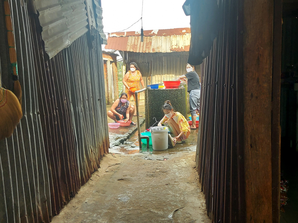 Các nữ công nhân ở khu nhà trọ Ao Sen đang dùng chung nước giếng bơm ở một bể chứa nước 