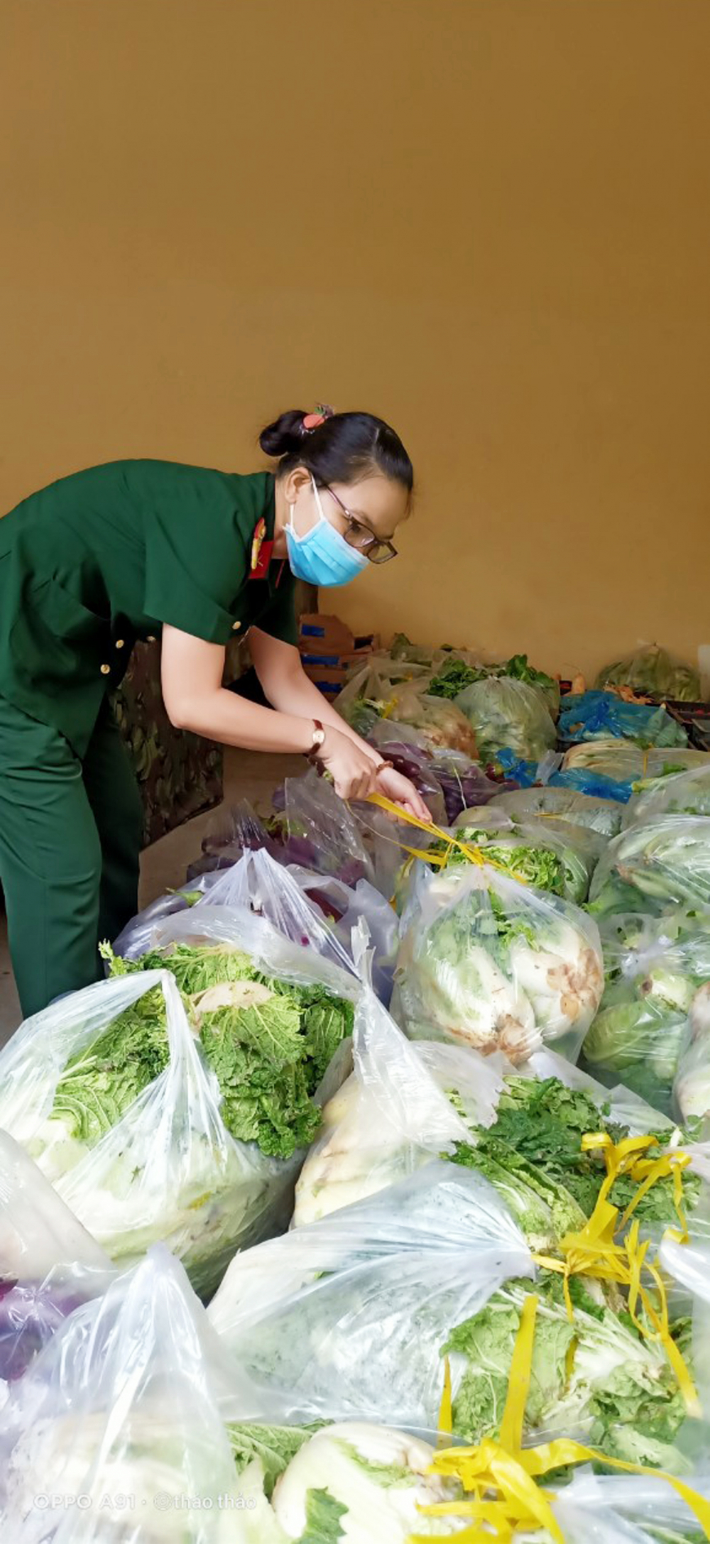 Đại úy Nguyễn Thị Thu Thảo đang phân rau do các mạnh thường quân gửi tặng để mang ra phiên chợ 0 đồng hỗ trợ cho người dân trong những ngày chống dịch căng thẳng