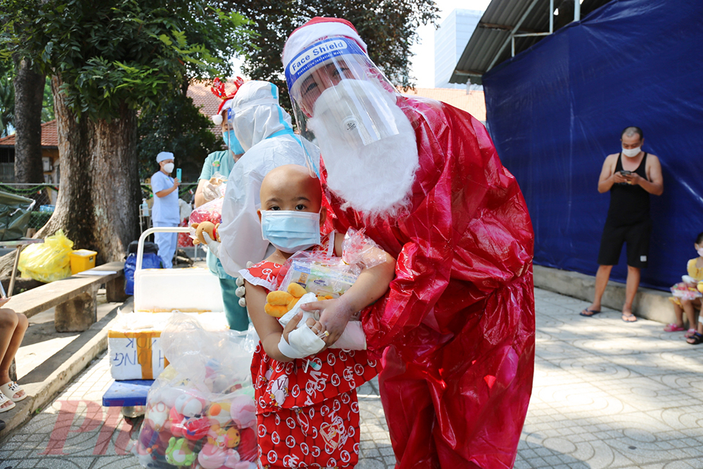 ộ lý Nguyễn Thị Bích Hạnh - khoa Nhiễm hóa thân thành bà già Noel mang túi quà khổng lồ đến với các bé đang mắc COVID- 19, các con vừa ngạc nhiên vừa thích thú khi nhận quà từ bà già Noel
