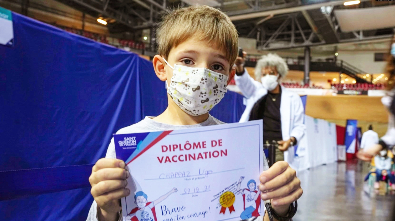 Hugo Chappaz (9 tuổi) khoe “bằng tốt nghiệp tiêm chủng” sau buổi chủng ngừa COVID-19 tại Paris hôm 22/12 - ẢNH: AP