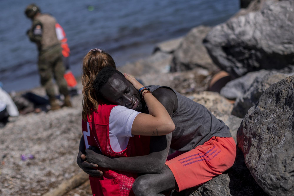 Một người di cư được an ủi bởi một thành viên của Hội Chữ thập đỏ Tây Ban Nha tại vùng đất Ceuta của Tây Ban Nha gần biên giới Ma-rốc và Tây Ban Nha, vào ngày 18/5
