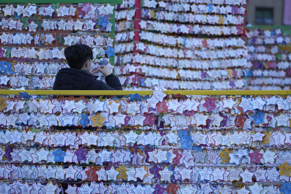 Một người đàn ông treo tờ giấy ghi lời chúc năm mới của mình vào đêm giao thừa tại ngôi đền Jogye ở Seoul, Hàn Quốc