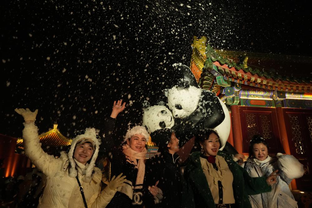 Những người tham dự sự kiện trùng đêm giao thừa vui đùa khi tuyết giả từ máy tạo bọt được thổi bay trên cao ở Bắc Kinh