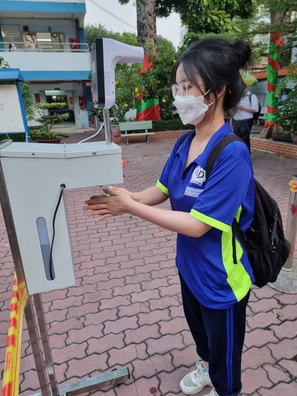 Học sinh Trường THPT Nguyễn Du (quận 10) thực hiện khử khuẩn, đo nhiệt độ trước khi vào lớp