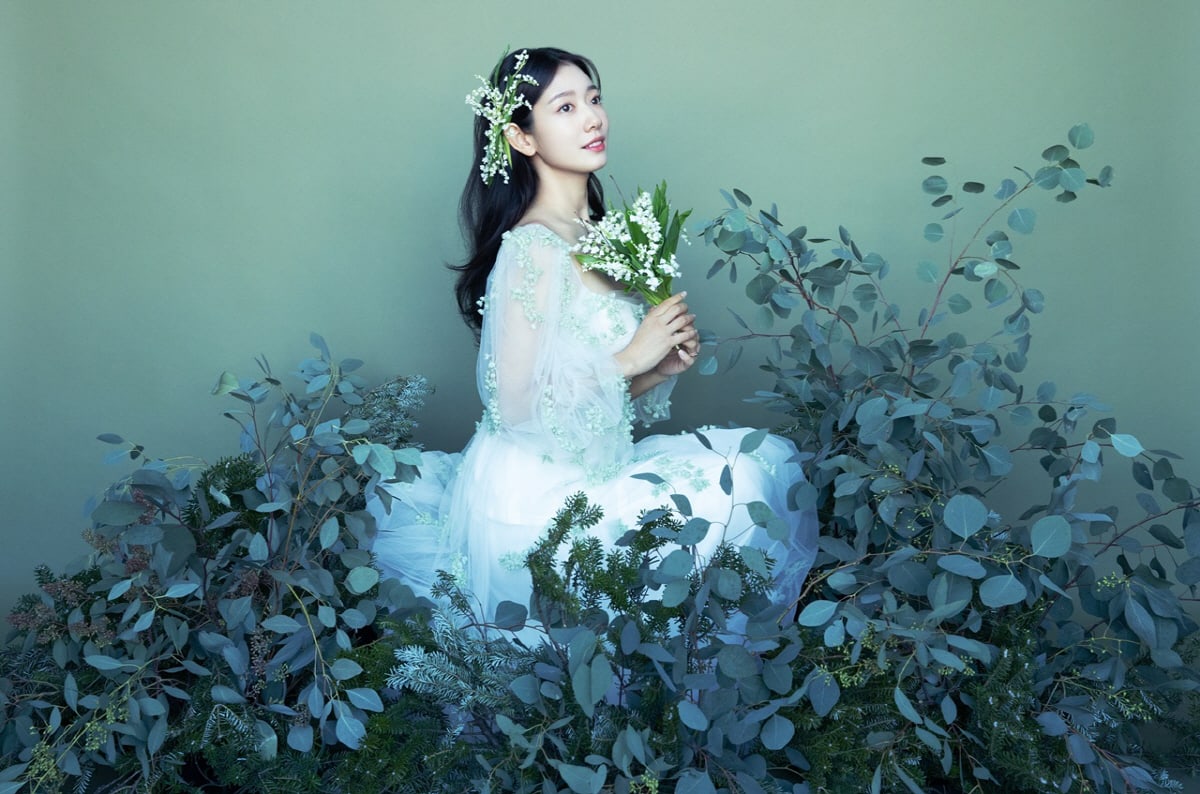 Cô dâu diện váy trắng tinh khôi, ngồi giữa không gian đầy hoa lá như một nàng công chúa bước ra từ trong truyện cổ tích. Các thiết kế váy cưới khá đơn giản, không cầu kỳ về họa tiết càng giúp cô nàng tôn lên nét đẹp tự nhiên