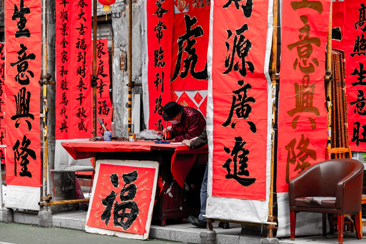Một ông đồ ở thành phố Phật Sơn, tỉnh Quảng Đông (Trung Quốc) đang cặm cụi viết những câu đối Tết - Ảnh: Chen Yufeng/VCG/Getty Images.