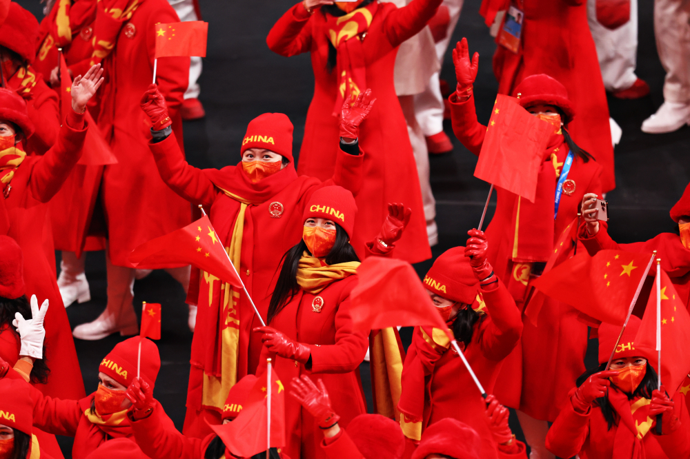 Các thành viên của Đội Trung Quốc vẫy cờ trong Lễ khai mạc Bắc Kinh 2022, khi đèn sân vận động chuyển sang màu đỏ rực
