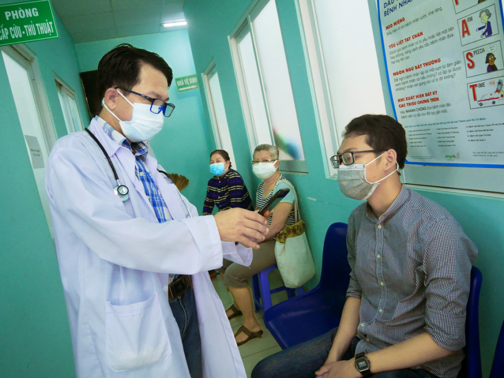 Bác sĩ Đinh Quang Nhân trò chuyện với các bệnh nhân đến khám bệnh ở Trạm Y tế P.22