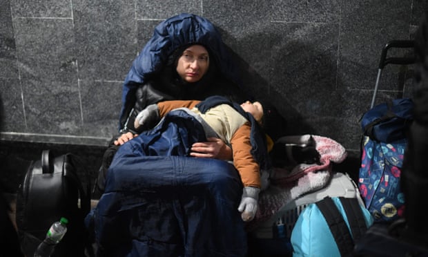 Một người phụ nữ ôm đứa con đang ngủ khi ngồi dưới đất ở ga tàu trung tâm Lviv. Ảnh: Daniel Leal / AFP / Getty Images