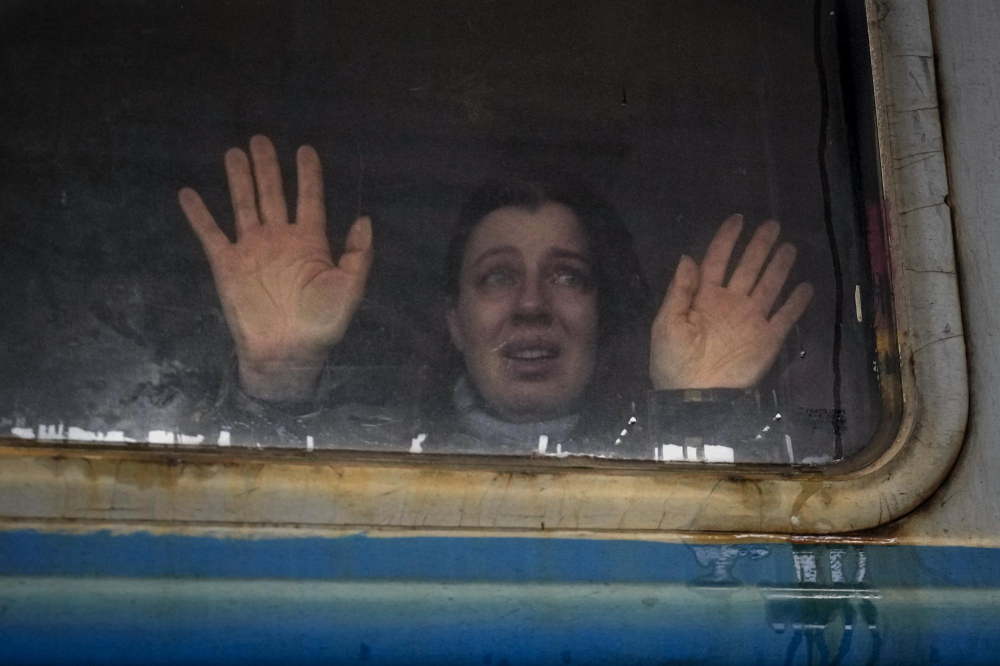 Một người phụ nữ nhìn về phía người thân và áp hai lòng bàn tay vào cửa sổ của một đoàn tàu đến Lviv, trên sân ga ở Kyiv, Ukraine