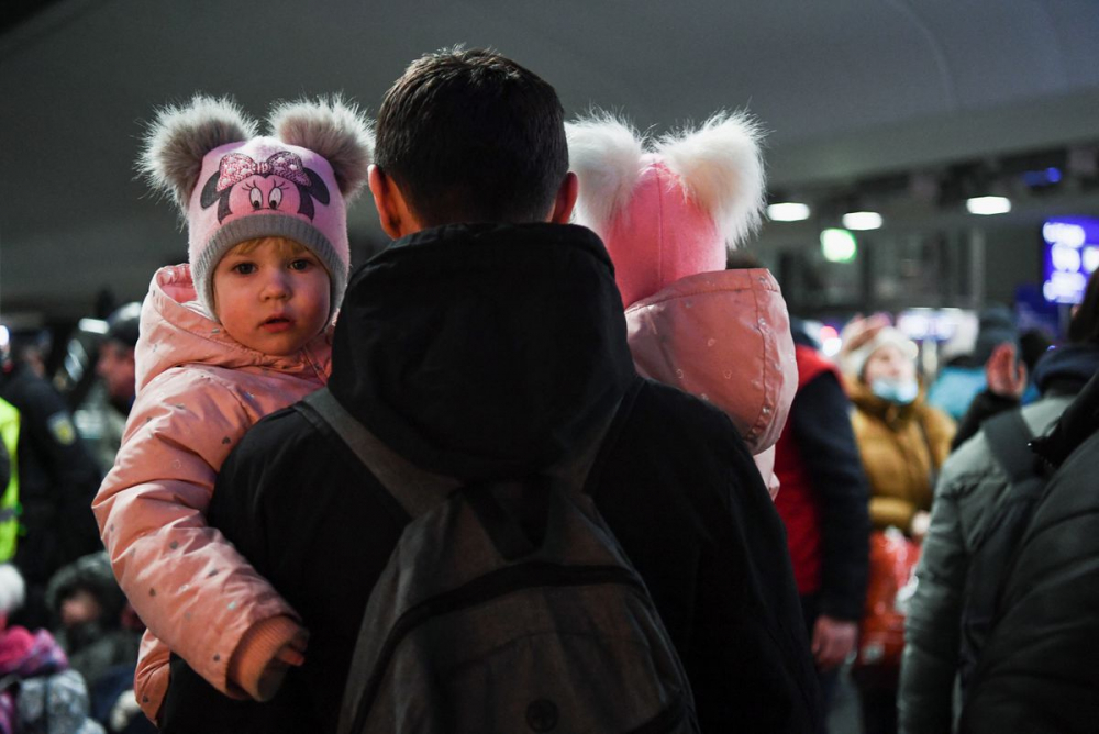 Một người đàn ông bế hai đứa trẻ bước xuống chuyến tàu từ Ba Lan đến ga xe lửa trung tâm của Berlin hôm 3/3