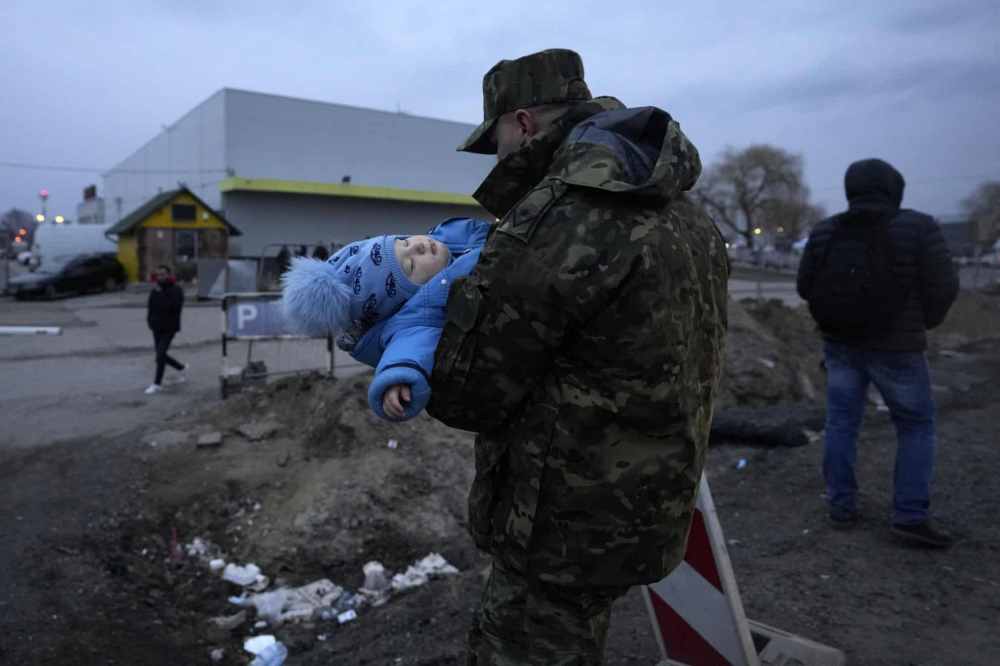 Người lính Ba Lan bế một em bé Ukraine đến cùng cha mẹ tại cửa khẩu biên giới ở Medyka, Ba Lan