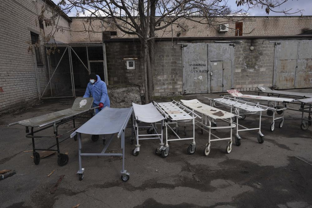 Một công nhân nhà xác di chuyển những chiếc cáng dùng để di chuyển thi thể người thiệt mạng trước khi họ được chôn cất ở ngoại ô Mariupol