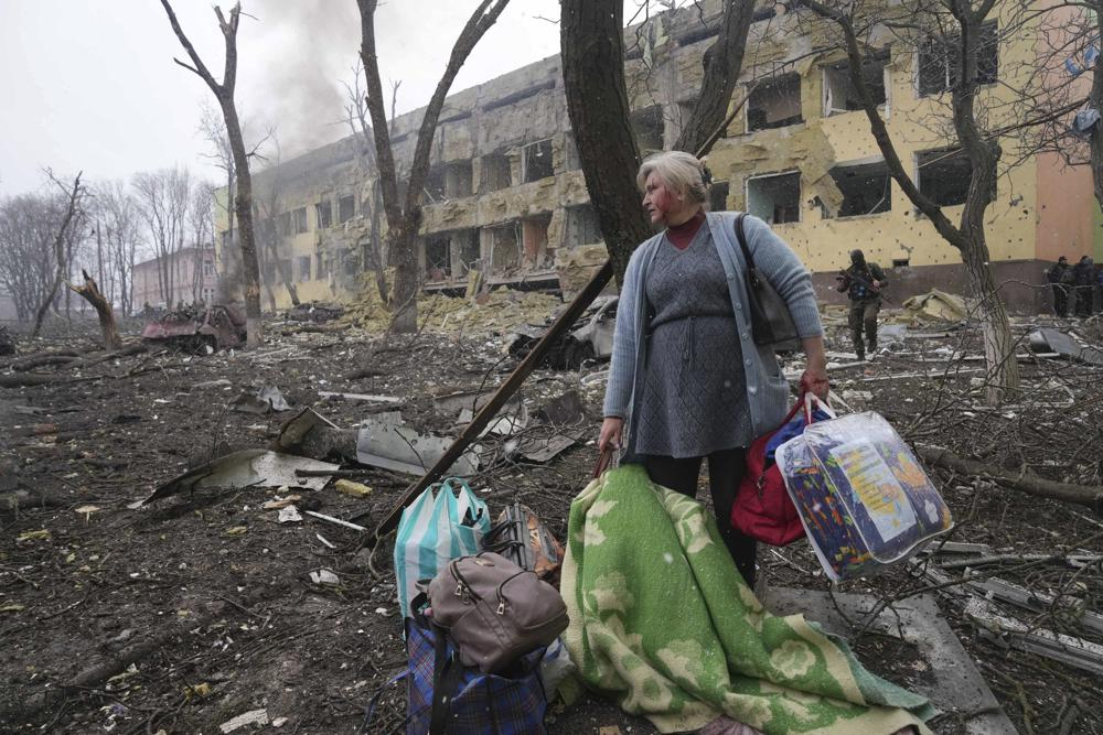 Một phụ nữ đi bên ngoài bệnh viện phụ sản ở Mariupol, cơ sở bị hư hại do pháo kích 