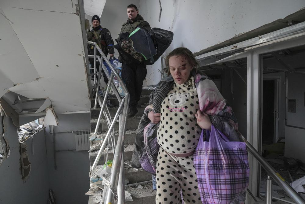 Một phụ nữ mang thai bị thương đi xuống cầu thang trong bệnh viện phụ sản bị hư hại do pháo kích ở Mariupol, Ukraine