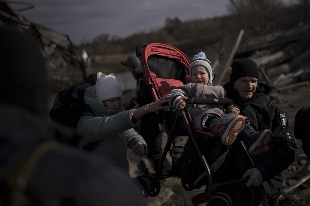 Một đứa trẻ được bế trên xe đẩy khi chạy trốn khỏi Irpin, ngoại ô Kyiv