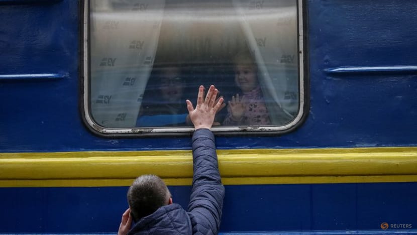 Những đứa trẻ nhìn ra khỏi chuyến tàu sơ tán từ Kyiv đến Lviv khi tạm biệt cha mình tại ga tàu trung tâm Kyiv ở miền trung Kyiv, Ukraine, ngày 3 tháng 3 năm 2022. (Reuters / Gleb Garanich)