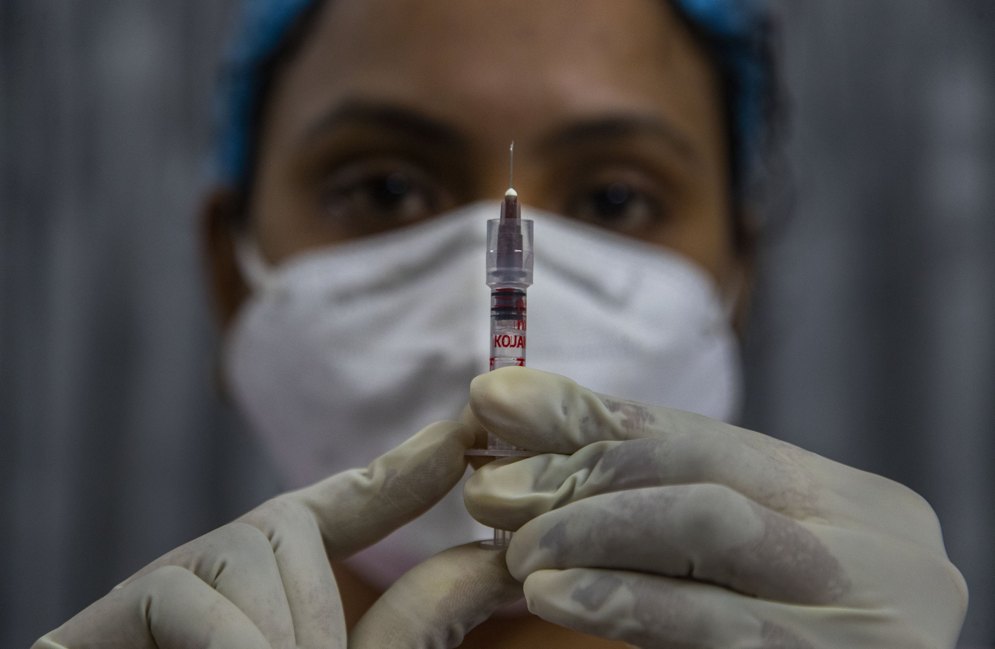 Nhân viên y tế kiểm tra ống tiêm trước khi tiêm vắc xin ở Ấn Độ.