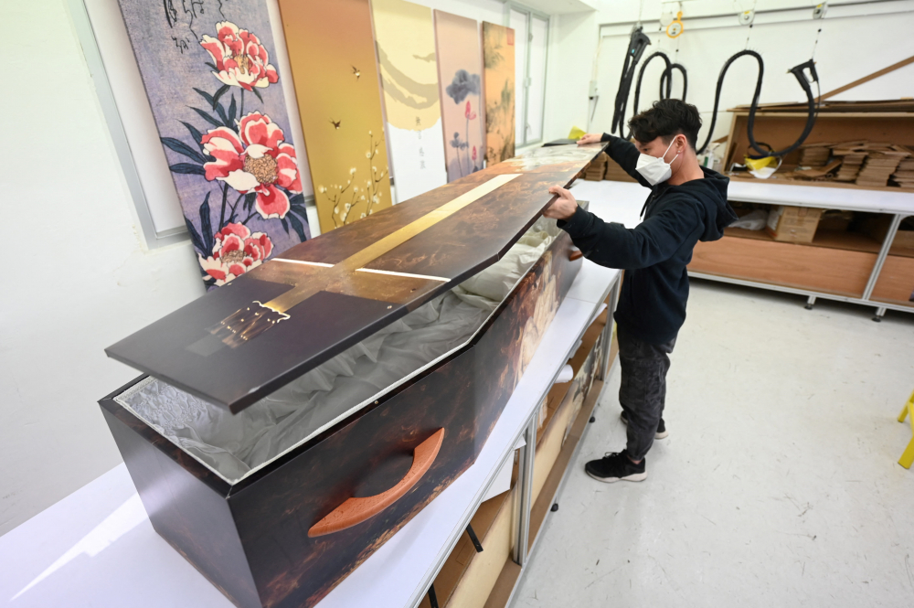 Một nhân viên của LifeArt Asia đang đậy nắp một chiếc quan tài sinh thái làm từ sợi gỗ tái chế tại nhà máy của họ ở Hồng Kông vào ngày 30/3