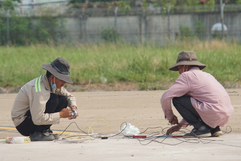 Hiện nay, các khu vực dường lăn hệ thống đèn tín hiếu đã được lắp đặt và đang chờ đấu nối dây điện. Trong ảnh, hai công nhân đang thực hiện 