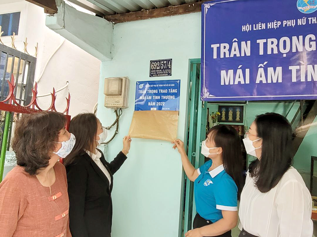 Bà Huỳnh Thị Hồng (bìa trái) xúc động nhận ngôi nhà mới nâng cấp