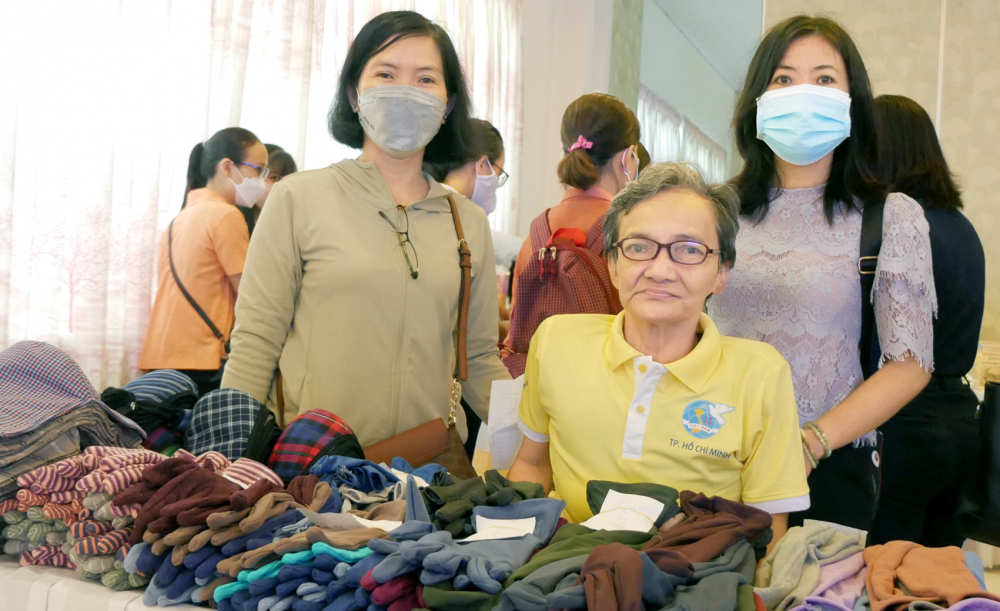 Chị Nguyễn Thị Ngọc Mai (ở giữa) được hỗ trợ gian hàng trưng bày khẩu trang, bao tay vải  do chị may và được cho vay vốn không lãi trong ngày hội “Vẻ đẹp vầng trăng khuyết”