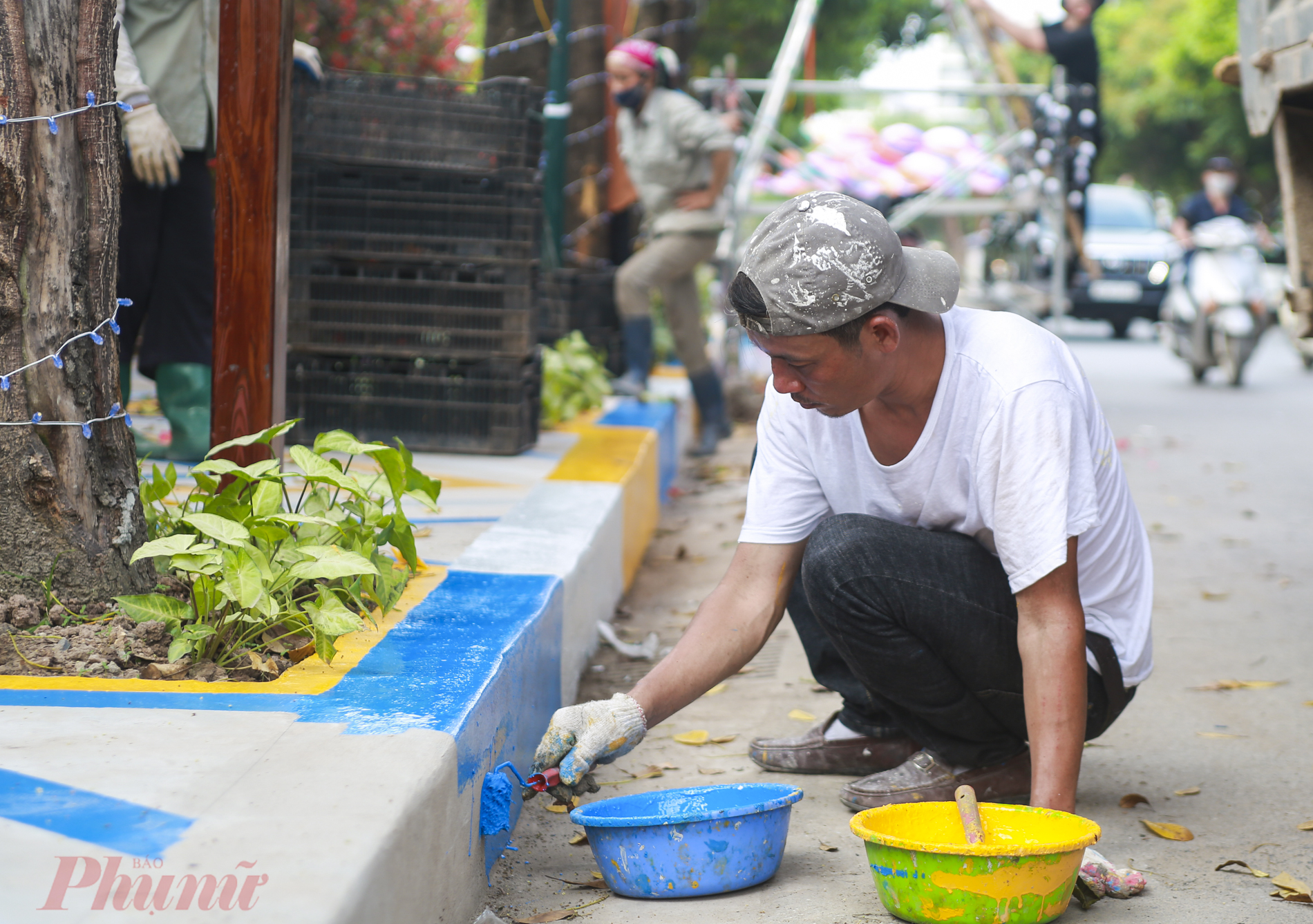 Thợ sơn đang sơn kẻ vỉa hè, lan can tại không gian đi bộ.