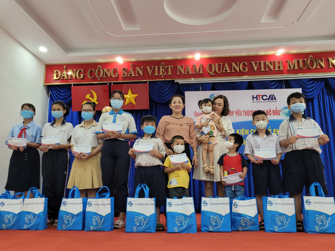 Bà Lê Thị Thu Hương - Chủ tịch Hội Tư vấn và đại lý thuế TP.HCM cùng các thành viên của Hội trao sổ tiết kiệm cho các trẻ mồ côi cha mẹ vì COVID-19