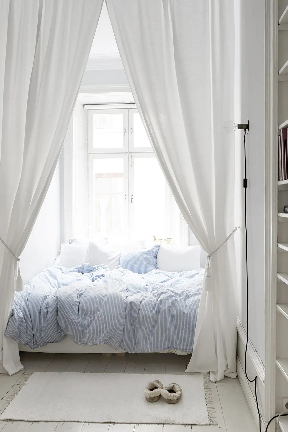 Treo những tấm rèm cao đến trần nhà xung quanh giường sẽ trông ấn tượng và mơ mộng hơn so với những chiếc rèm cửa kiểu cổ điển. Chăn ga gối đệm màu xanh da trời trong phòng ngủ này tạo thêm điểm nhấn vui tươi.