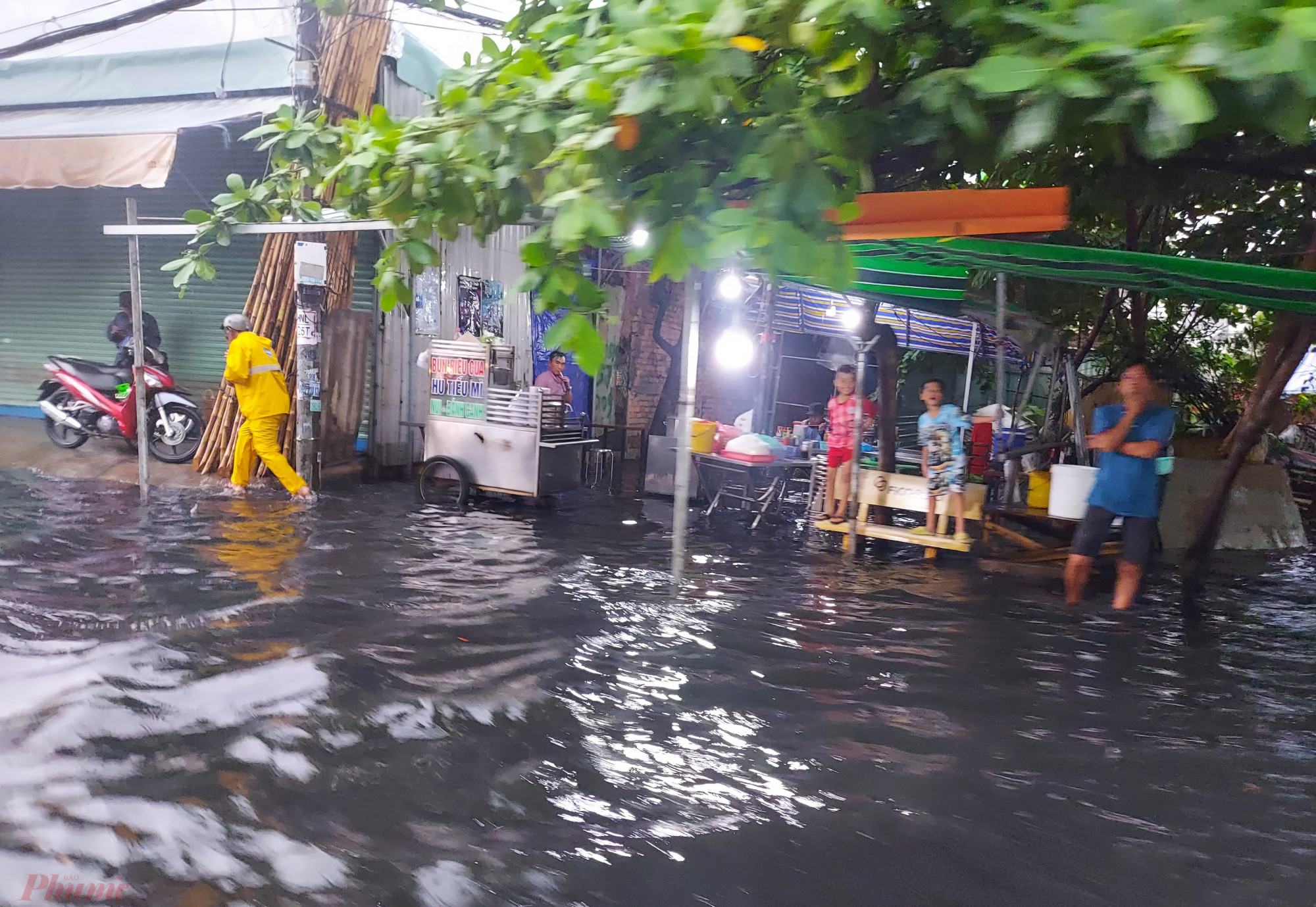Một quán ăn bị ngập nước, chủ quán chỉ biết đứng chống cằm nhìn ra đường chờ nước rút.