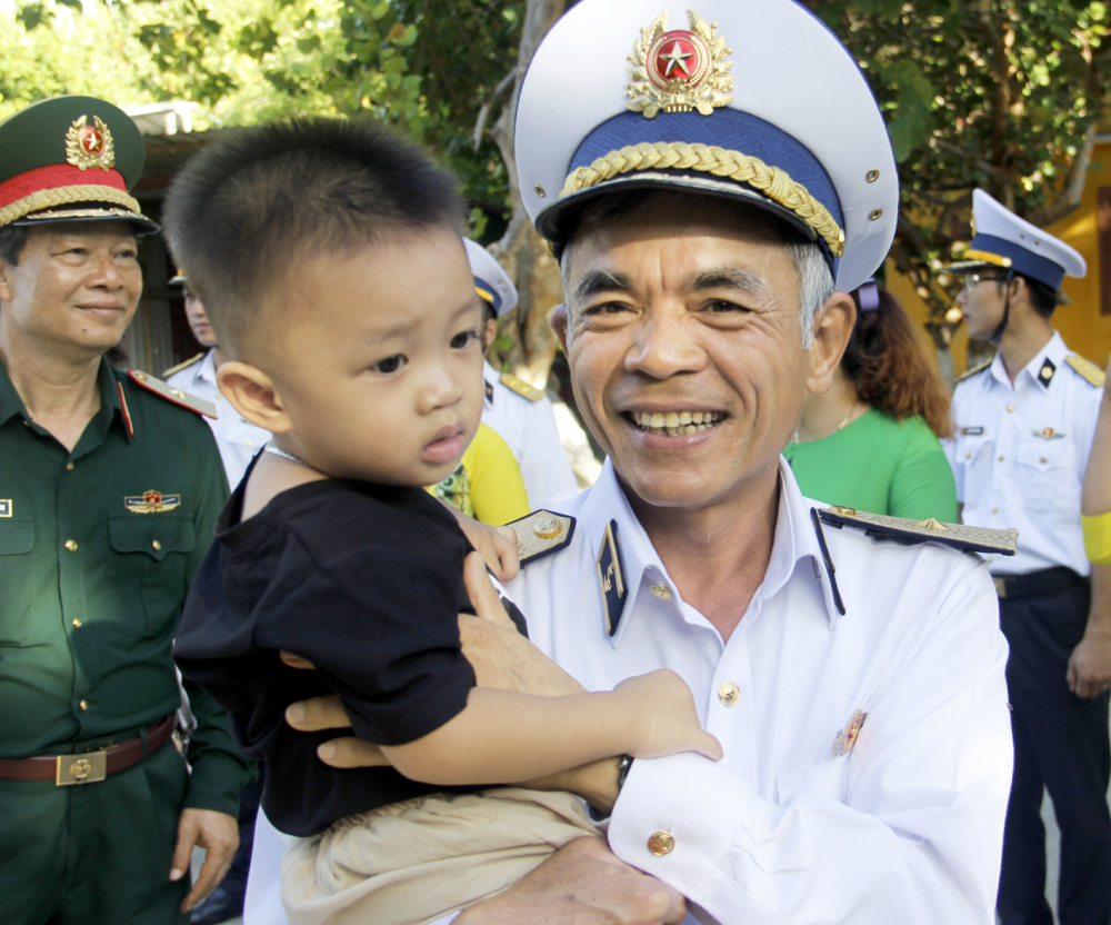 Chuẩn đô đốc Lương Việt Hùng - Phó Tư lệnh Quân chủng Hải quân - bế một cháu bé được đăng ký hộ khẩu trên đảo Sinh Tồn