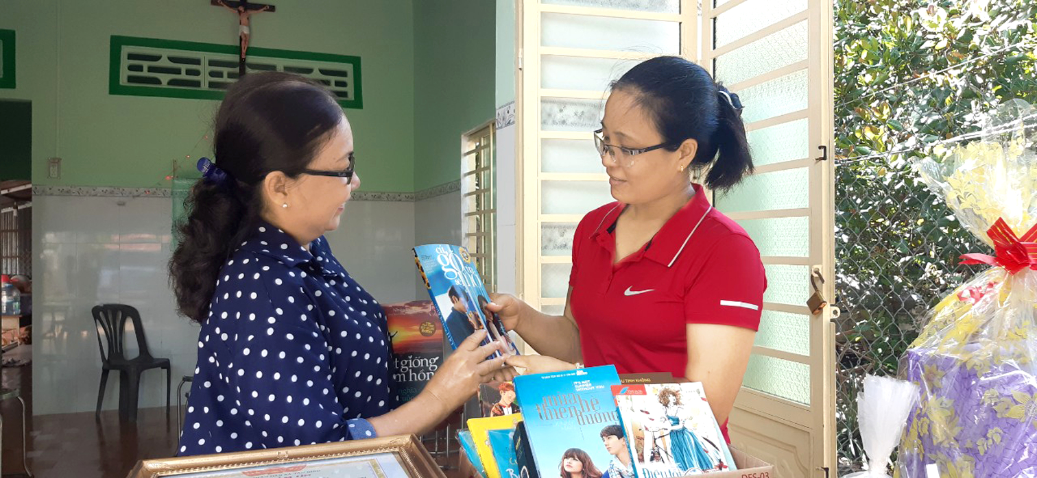 Ngày cô giáo Nguyễn Thị Ngọc (bìa phải) vào nhà mới, quà tặng của cô Võ Thị Bích Vân (bìa trái) ngoài những đồ gia dụng còn có một thùng sách để làm tủ sách cho học trò