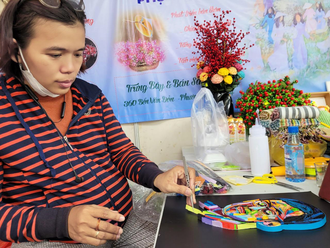 Trần Thụy Thúy Vi tận dụng những phút giây rảnh rỗi để dần hoàn thiện một bức tranh do khách đặt hàng tại hội chợ trưng bày sản phẩm ở công viên Khánh Hội trong tuần vừa qua