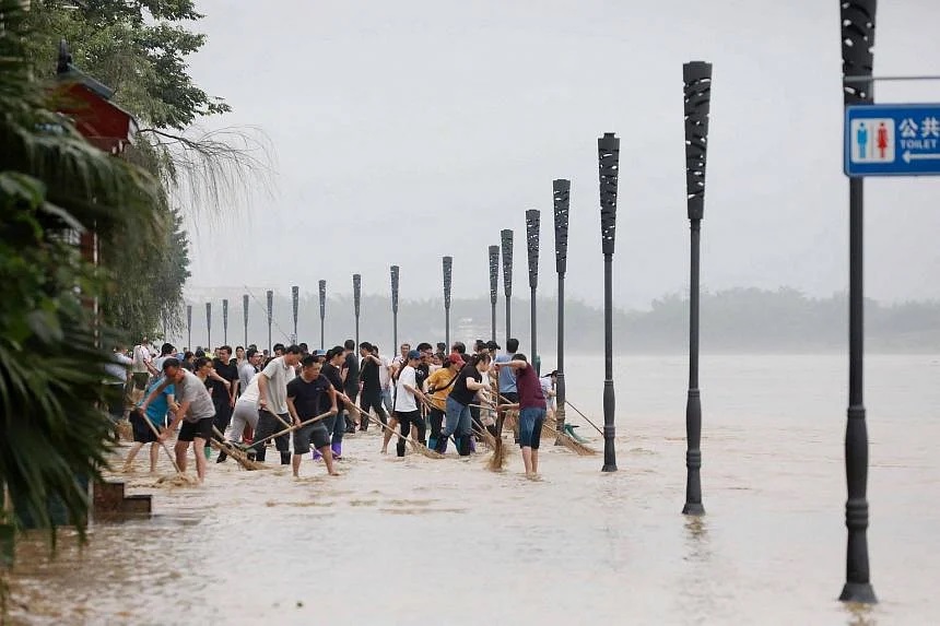 Người dân dọn dẹp một con phố bị ngập lụt do mưa lớn ở Rongan, khu vực phía nam Quảng Tây của Trung Quốc, vào ngày 5/6