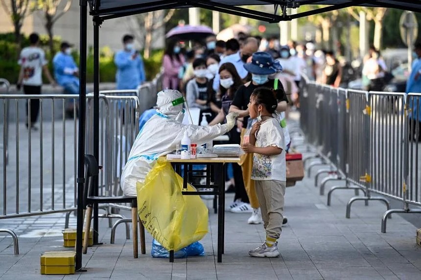 Nhân viên y tế lấy mẫu xét nghiệm COVID-19 của một đứa trẻ tại điểm xét nghiệm tạm thời ở Bắc Kinh, vào ngày 2/6