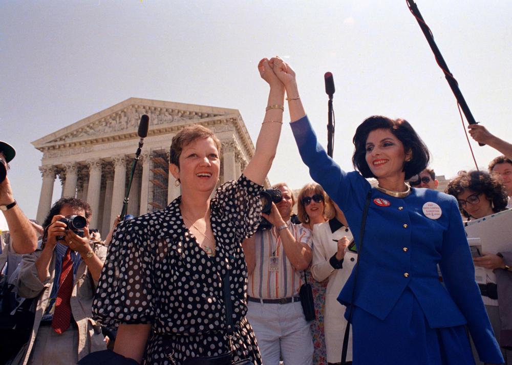 Jane Roe trong phiên tòa năm 1973 (trái) và luật sư Gloria Allred của cô nắm tay nhau khi họ rời tòa nhà Tòa án Tối cao ở Washington, ngày 26/4/1989