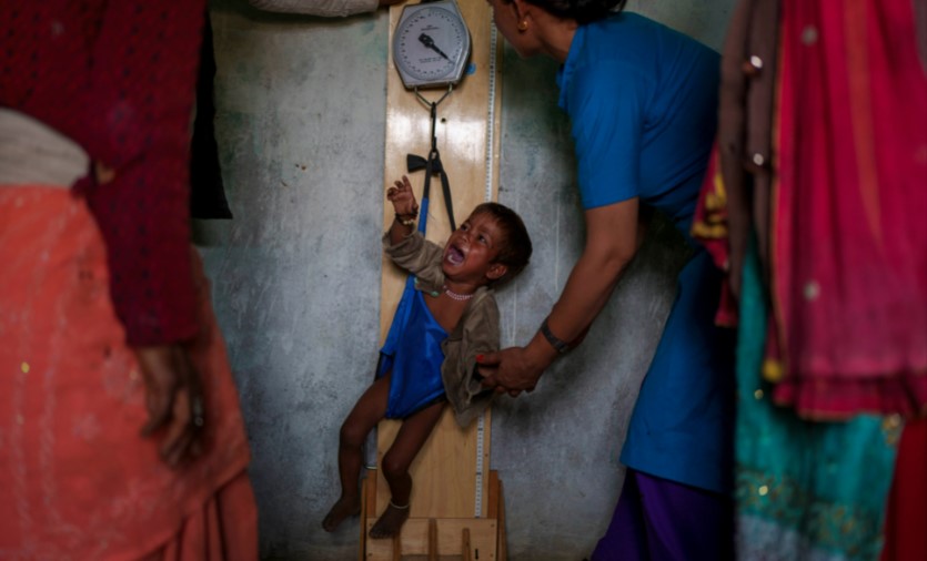 Một nhân viên y tế kiểm tra cân nặng của một hội trẻ suy dinh dưỡng tại y tế ở Muktikot. [Niranjan Shrestha / Al Jazeera]