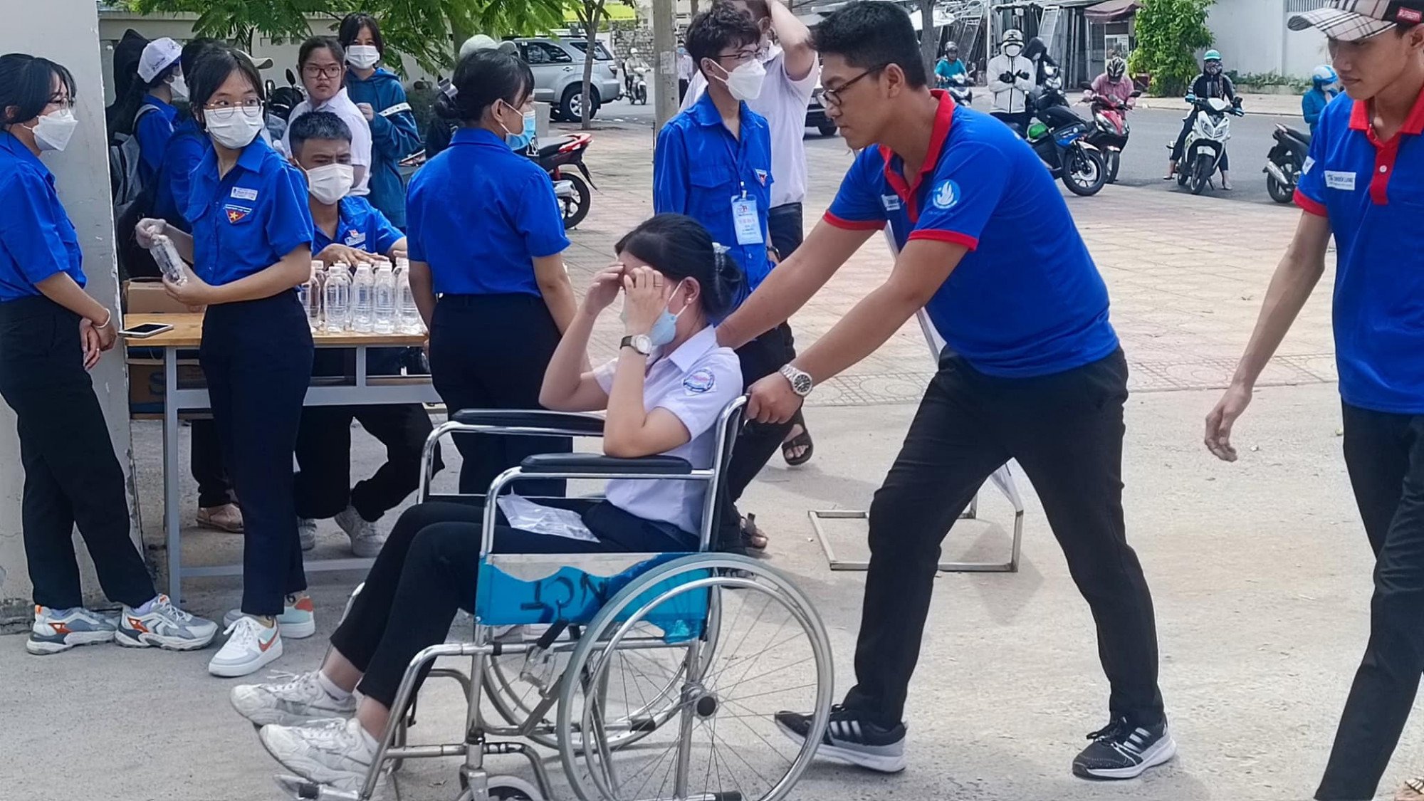 Các tình nguyện viên tiếp sức mùa thi Trường Cao đẳng kỹ thuật công nghệ Nha Trang đẩy xe lăn giúp thí sinh Cát Tiên vào phòng thi