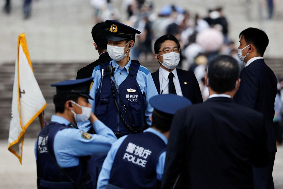 Các nhân viên cảnh sát đứng gác khi mọi người xếp hàng để dâng hoa tại chùa Zojoji