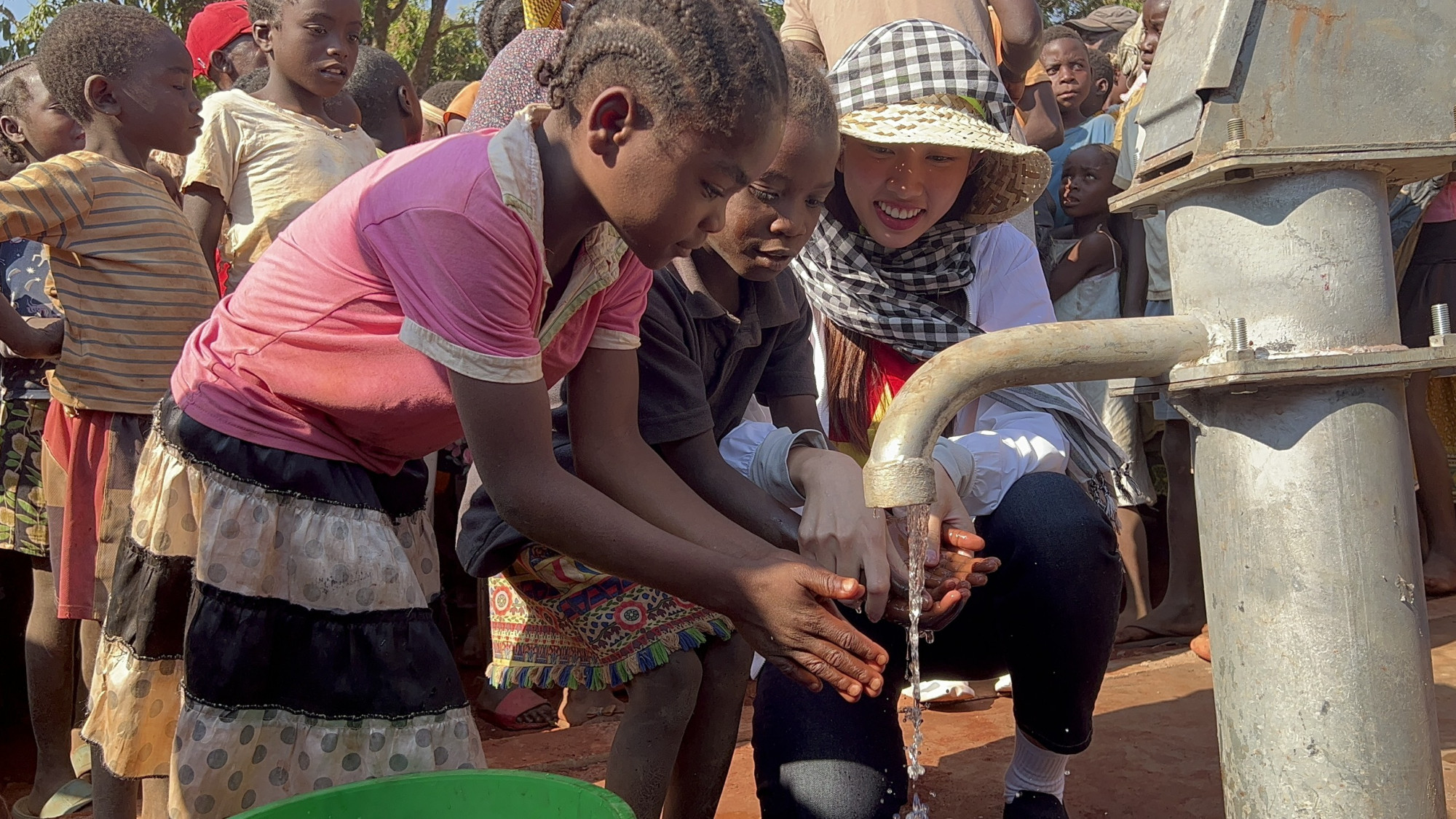 Thuỳ Tiên và trẻ em địa phương hứng những làn nước sạch đầu tiên từ giếng