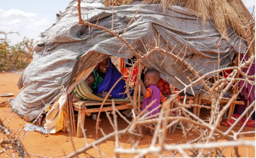 Cậu bé Gedi chơi với em gái và mẹ bên trong một căn lều tạm bợ tại trại Kaharey IDP ở Dollow, Somalia. Ngôi nhà của họ được làm bằng những cành cây buộc lại với nhau để tạo thành mái vòm. Chăn, bạt và các mảnh vải được gắn chặt vào cấu trúc để bảo vệ chúng khỏi sức nóng không ngừng. Hạn hán và đói kém buộc gia đình phải rời bỏ nhà của họ ở Garbaharrey, họ đi bộ hơn 10 ngày để đến trại. [Fazel / UNICEF]