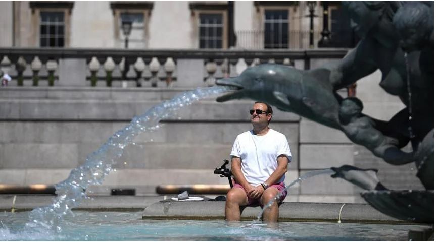 Một người đàn ông ngồi bên đài phun nước ở Quảng trường Trafalgar ở London