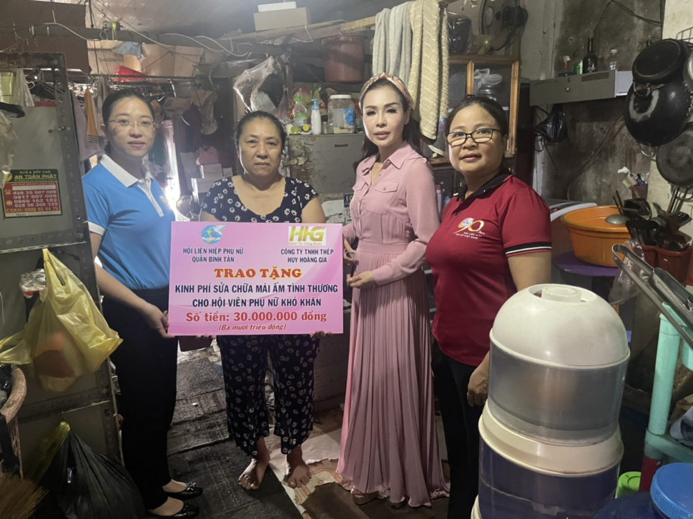 Chị Huỳnh Đặng Hà Tuyên (bìa trái) - Chủ tịch Hội LHPN quận Bình Tân - trao bảng tượng trưng kinh phí hỗ trợ sửa nhà cho gia đình chị Kim Hồng. 