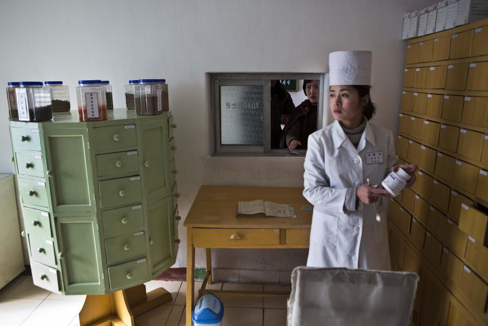 Một dược sĩ tại Phòng khám Kaeson ở quận Moranbong của Bình Nhưỡng, Triều Tiên bốc thuốc Koryo truyền thống cho một bệnh nhân đang đợi bên ngoài