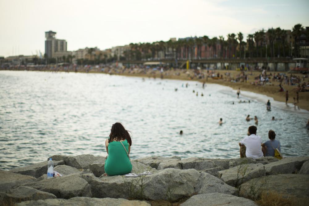 Một người phụ nữ ngồi bên bãi biển ở Barcelona, Tây Ban Nha. Quan niệm bảo thủ về cái đẹp khiến nhiều phụ nữ cảm thấy tự tin khi ra biển