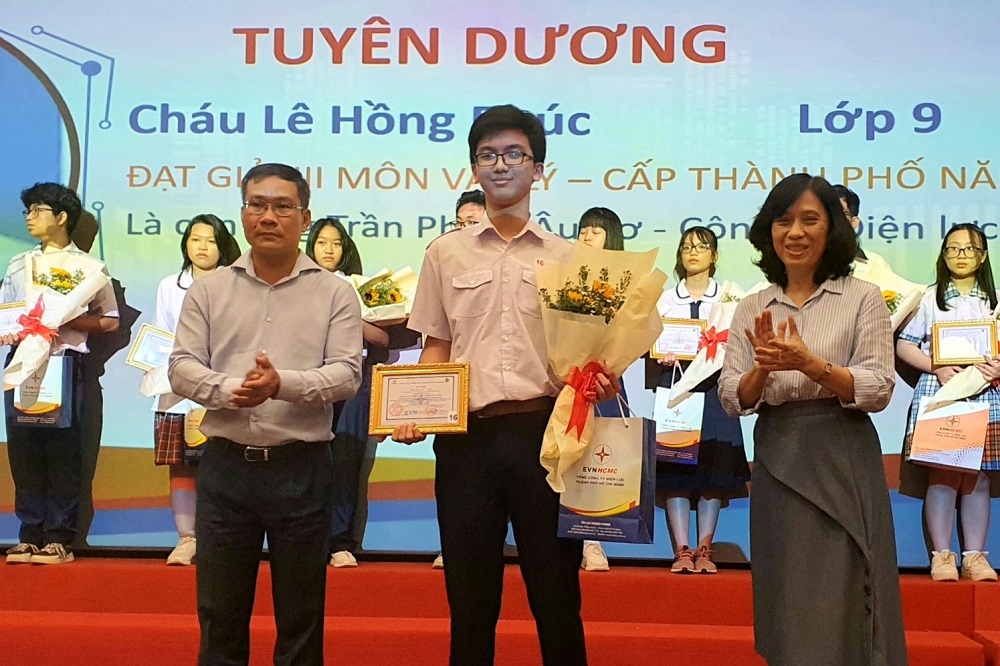 Bà Đỗ Thị Xuân Chi - thành viên Hội đồng Thành viên, ông Bùi Trung Kiên - Phó tổng giám đốc EVNHCMC trao giấy khen và phần thưởng cho các em học sinh giỏi - Ảnh: EVNHCMC